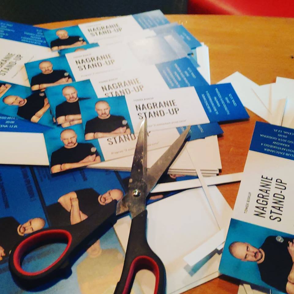 Na zdjęciu znajdują się bilety na stand up Tomka Biskupa oraz nożyczki.